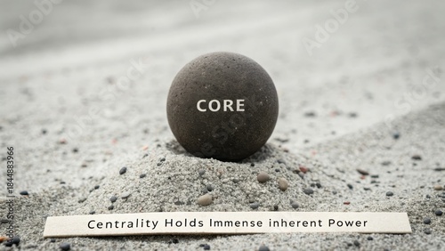 A heavy unpolished dark stone orb with the word CORE at its center, resting on sand.