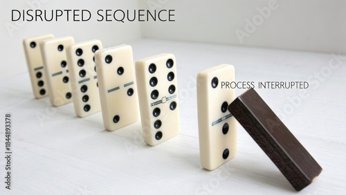 A structured sequence of white dominoes standing upright with one dark domino about to cause a chain reaction, representing process and progression