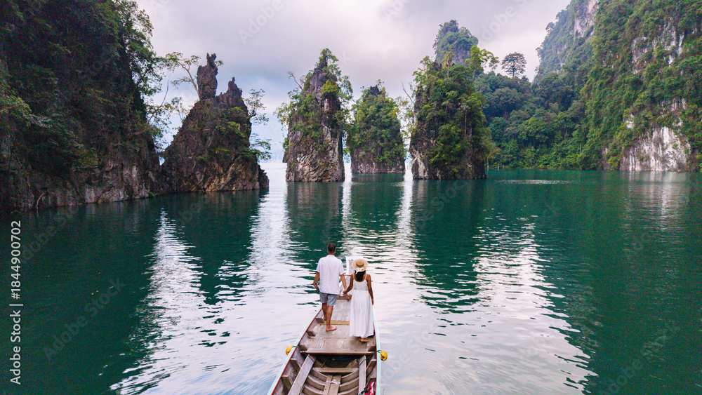 Naklejka premium Couple exploring the serene beauty of Cheow Lan Lake in Khao Sok, Thailand