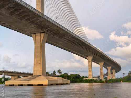 sunset view from beneath the Pumarejo Bridge over the Magdalena River in Barranquilla, Colombia, highlighting bridge pillars, structural design, river reflections and transportation infrastructure.