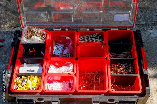 a storage box with compartments filled with building materials, nails, and fasteners