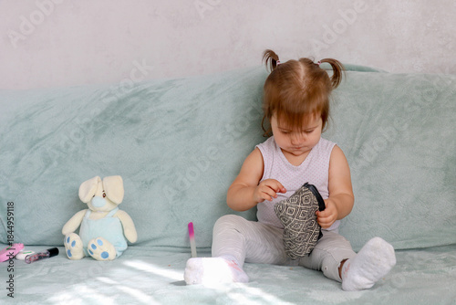 A funny girl carefully examines her mother's cosmetic bag