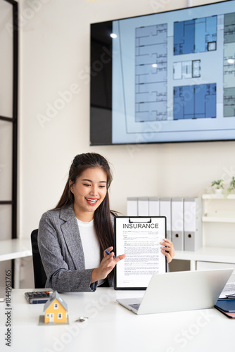 Online operation of buying and selling real estate. businesswoman realtor sit in office talks on a video call with clients, shows contract insurance to camera and offers product contract options.