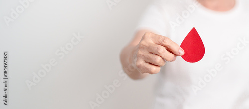 Elderly woman with red Blood drop paper for concept of June World Blood Donor day, Donation, January Blood donor awareness month, April Hemophilia awareness day, May Thalassemia Day, Anemia awareness