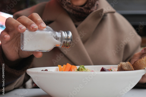 Fotografija Person adding seasoning to a bowl of food at a cafe