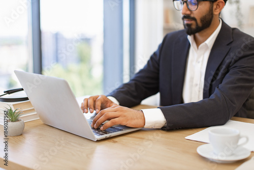 An Arab businessman is working on his laptop in a modern office setting