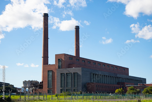 Принти на полотні Angled view of old brick building with two tall chimneys against a blue, cloudy