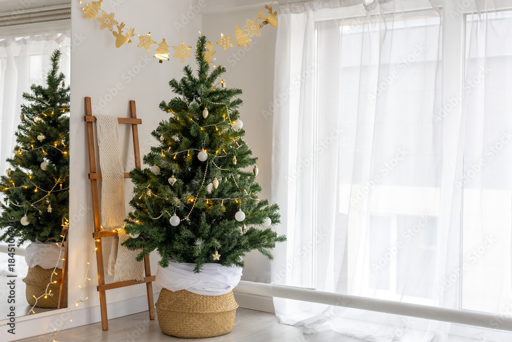 Fototapeta premium Christmas tree with gifts garlands in the white cloud dancer interior with large window and mirror for new year, copy space