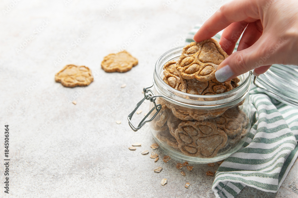 Naklejka premium Hand picking homemade paw print dog treats from jar