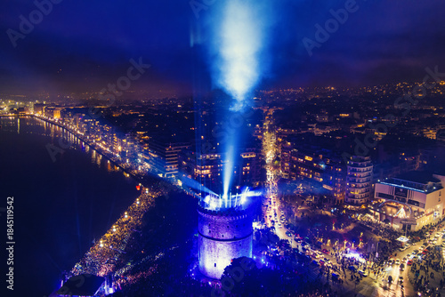 Fototapeta Naklejka Na Ścianę i Meble -  New Year’s Eve Gathering Around Thessaloniki White Tower with Festive Lights and Urban Energy