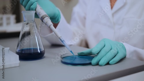 Close up female hands uses pipette for biochemical analysis, preparing agar media in a Petri dish