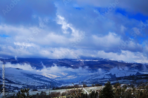 View of the snow-capped Carpathian Mountains with clouds lying on them on a winter day