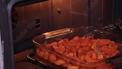 Preparing baked pumpkin in the oven, a delicious autumn dish made with pumpkin, feta cheese, and olive oil, a healthy and nutritious meal, with hands opening the oven door.