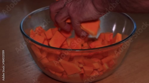 Preparing baked pumpkin in the oven, a delicious autumn dish made with pumpkin, feta cheese, and olive oil, a healthy and nutritious meal, with hands mixing the ingredients in a glass bowl.