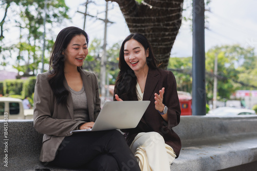 Asian businesswomen discussing online project using laptop