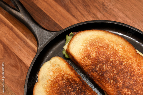 Turkey panini in a cast iron skillet with bacon, arugula and Swiss cheese