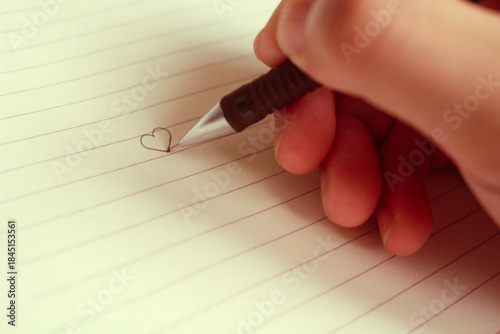 Focus on the hand drawing a heart on Valentine's Day.