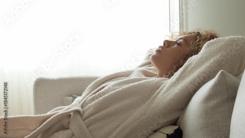 Young woman in bathrobe relaxing on sofa
