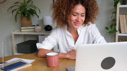 Young woman video calling with a laptop from her home office