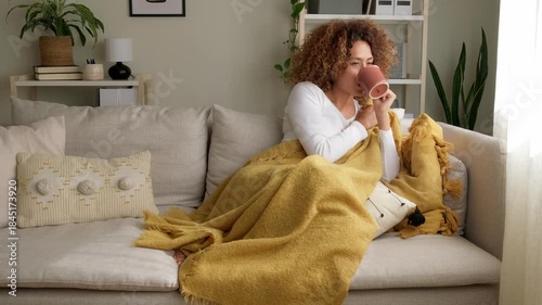 Cozy woman relaxing on a couch drinking tea