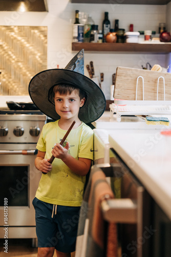 Boy playing wizard in kitchen holding magic wand