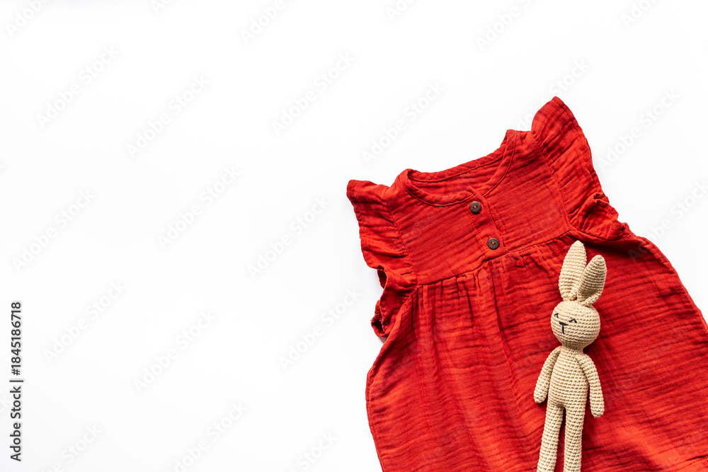 Φωτογραφία Baby girl red cotton muslin dress and knitted bunny toy, top view