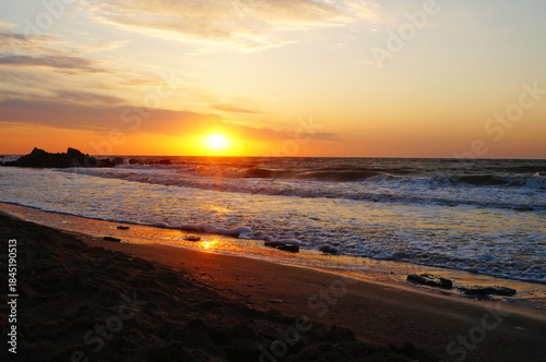 Sunrise on the seashore with waves on a warm summer morning