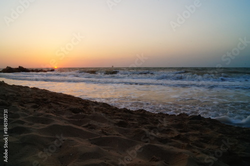 Sunrise on the seashore with waves on a warm summer morning