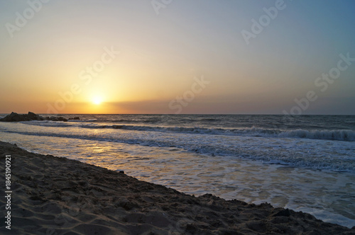 Sunrise on the seashore with waves on a warm summer morning