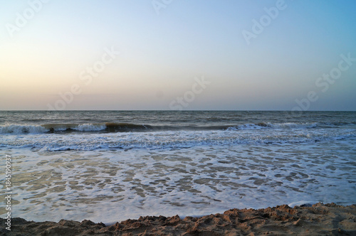 View of the sea from the coast on waves with foam on a summer day