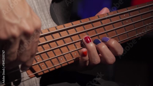 Close up of finger musician at the bass guitar , musician playing bass guitar in the room and with  spotlights ,Bassist practicing in a  studio.