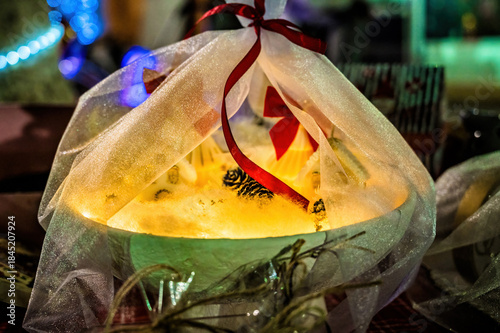 Festive glowing decoration wrapped in sheer fabric with red ribbon, warm light creating cozy holiday atmosphere, winter decor concept, magical illumination, handmade festive styling, romantic seasonal