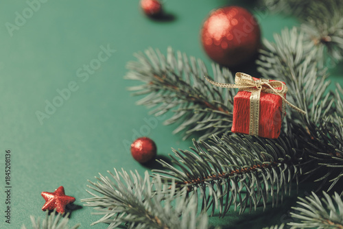 Christmas background with Christmas tree branches and small Christmas gift box close-up.