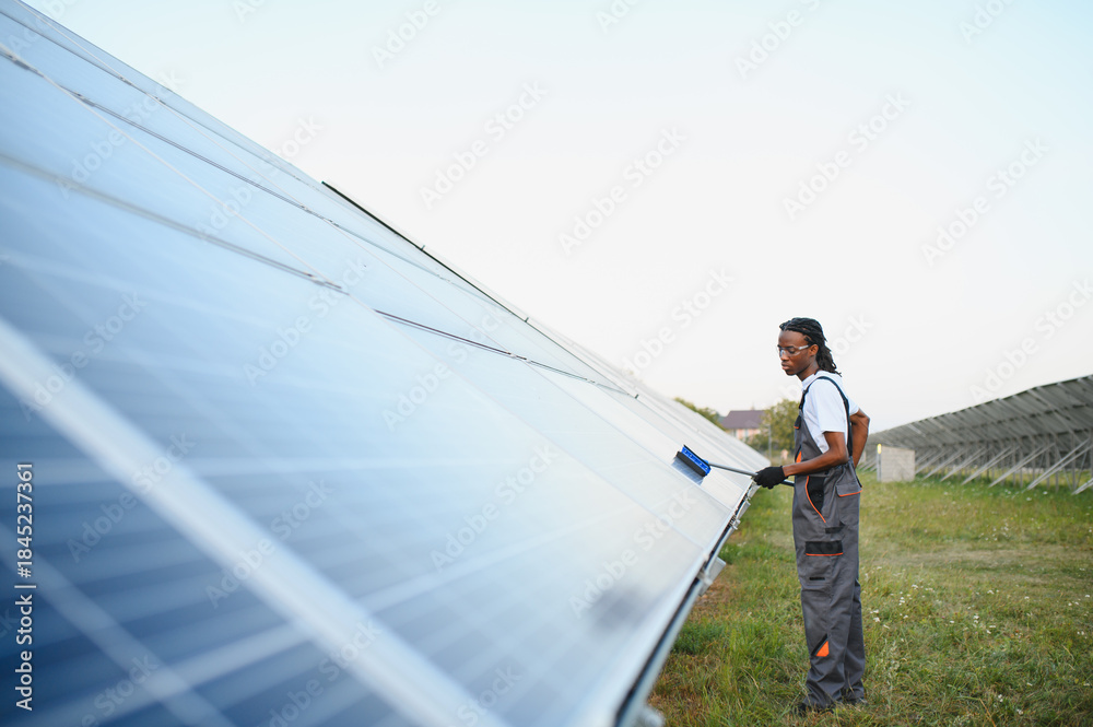 Naklejka premium African american man cleaning solar panel field