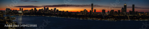 Aerial view of the Charles River reflects the fiery sunset behind the illuminated Boston skyline, revealing a vibrant contrast between water and city lights, Boston, Massachusetts, United States.