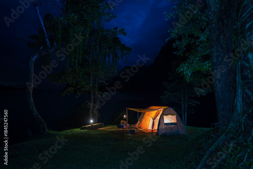 Night camping adventure with a cozy tent lit under the starry sky in a summer forest