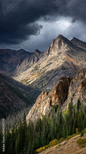 Dramatic Rocky Mountains Under Stormy Clouds with Sunlight.