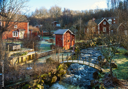 Swedish village of Rottle, by a rushing stream near Granna, Jonköping lan. Red wooden houses and frosty gardens nestled in peaceful nature, inviting slow travel and tranquil winter countryside escapes