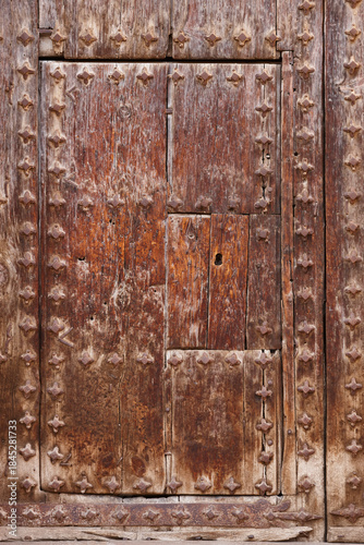 Ancient rusty wooden door decorated with nails. Vertical