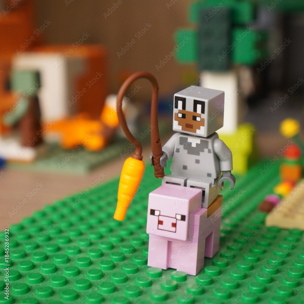 Fototapeta premium Minecraft Lego figure riding a pig with a carrot on a leash
