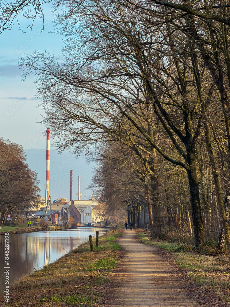 Obraz premium Pathway by the canal with industrial backdrop