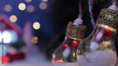 Large light bulbs decorated inside on a blurred background with a house and Christmas trees with a red car