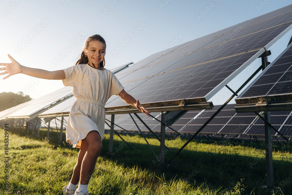 Fototapeta premium Running, having fun. Happy girl is near renewable energy equipment under bright sunlight