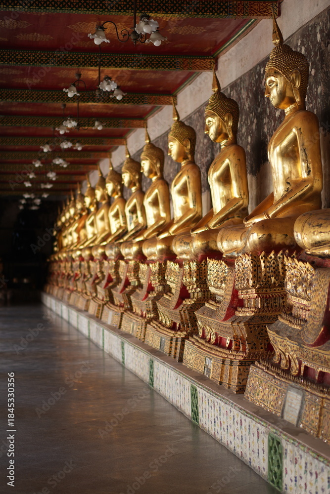 Fototapeta premium Portrait Buddha Statues in Corridor of Wat Suthat, Bangkok Thailand - One of Famous Ancient Temple in Bangkok