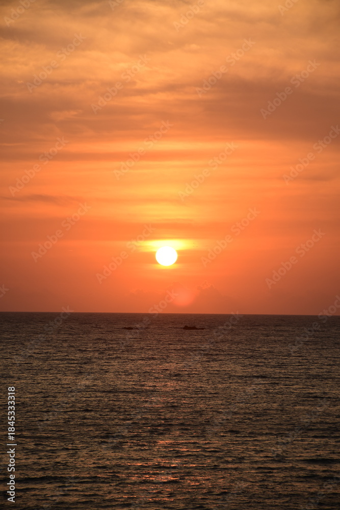 Fototapeta premium Breathtaking tropical seascape at golden hour/sunset, with sunlight reflecting on the calm ocean surface. Ideal for travel, background, and tranquility themes