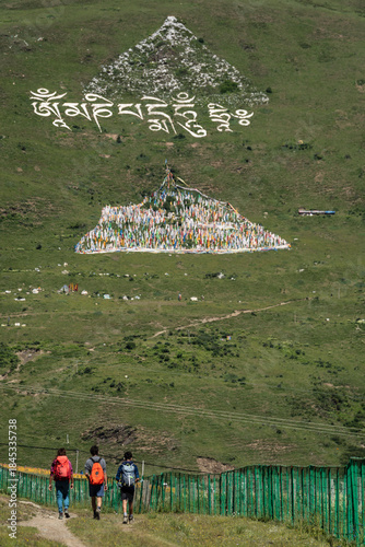 hikers on the trail and prayer flags on the hillside forming a triangle, Tagong (Lhagang), Garzê Tibetan Autonomous Prefecture, Sichuan,  China