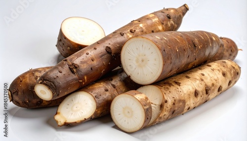 Cassava root pieces with rough brown skin and white starchy interior on white background.