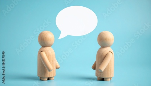 Two wooden figurines facing each other with speech bubble on light blue background.