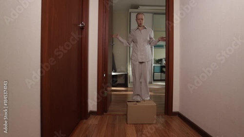 Cancer patient sitting in hallway with cardboard box, woman in pajamas receiving home delivery parcel after chemotherapy, online shopping and contactless courier service support during oncology