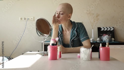 Bald woman carefully drawing eyeliner line, symbol of resilience, hope, and self-care for oncology patients.